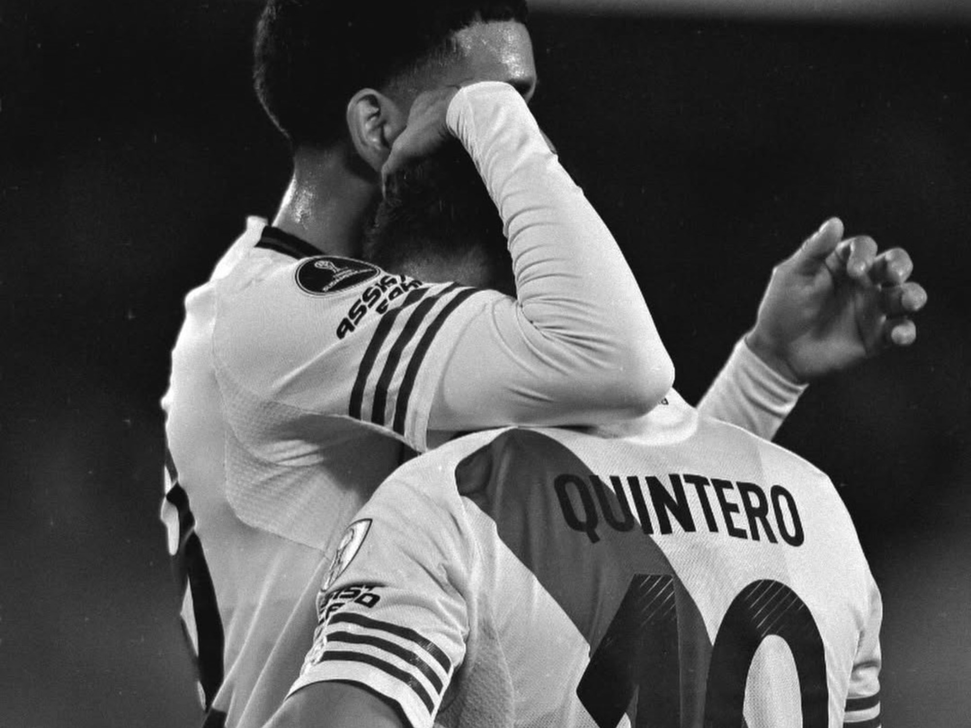 Jugadores de River Plate abrazándose en el campo de juego durante un partido.