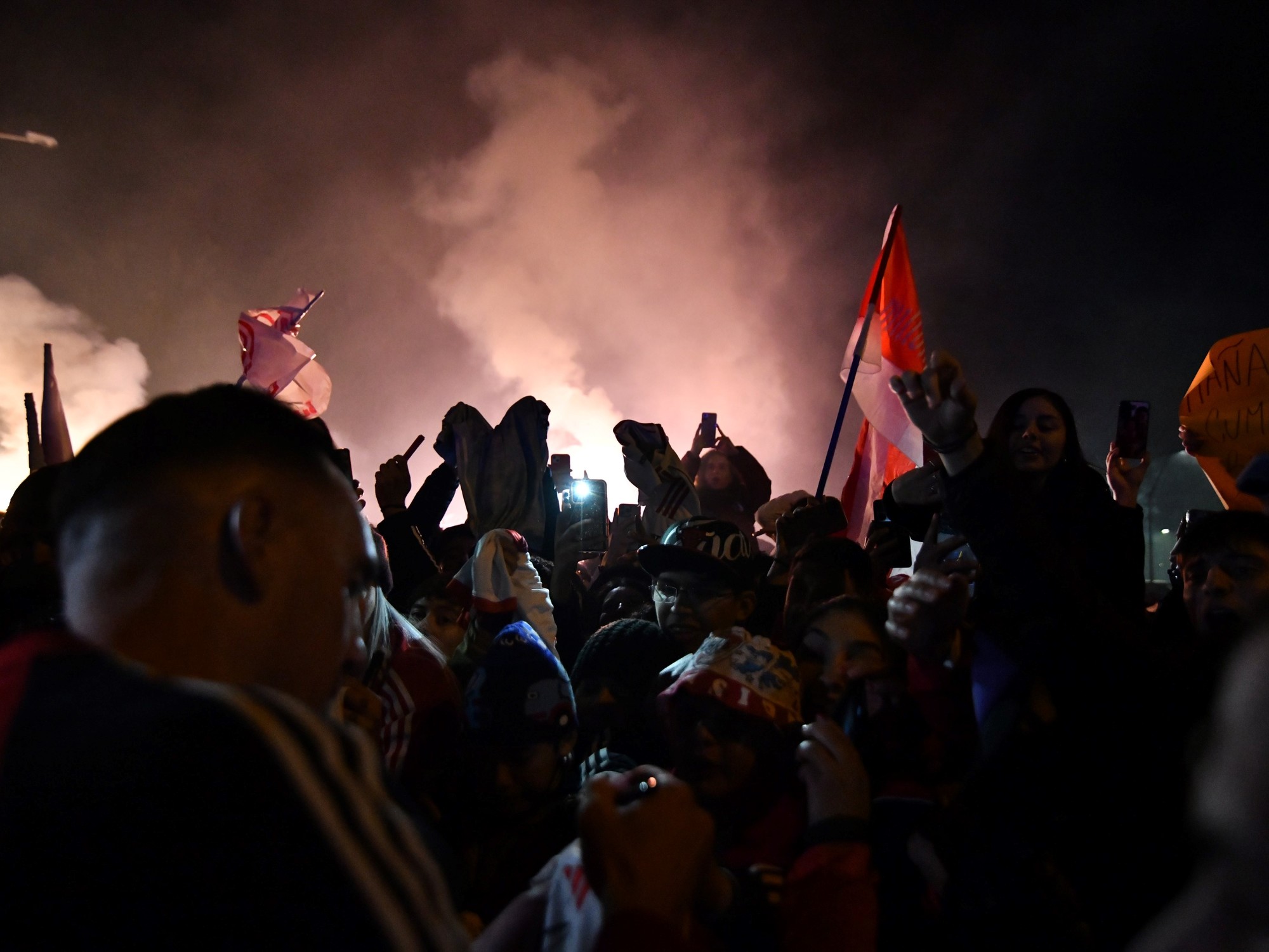 Hinchas de River Plate con banderas y fuegos artificiales recibiendo al plantel en Córdoba.