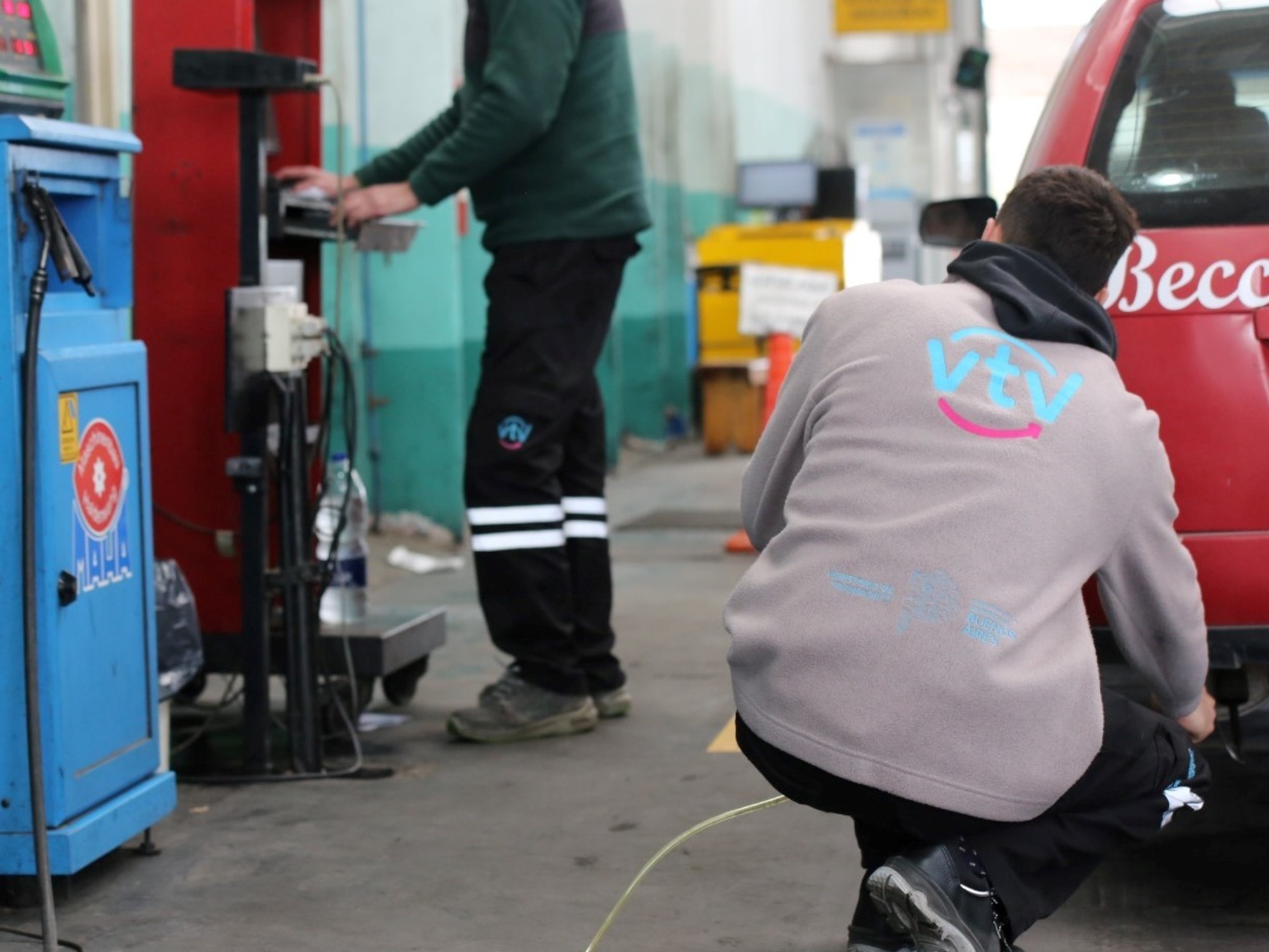 Operarios realizando la Verificación Técnica Vehicular (VTV) a un vehículo en un taller.