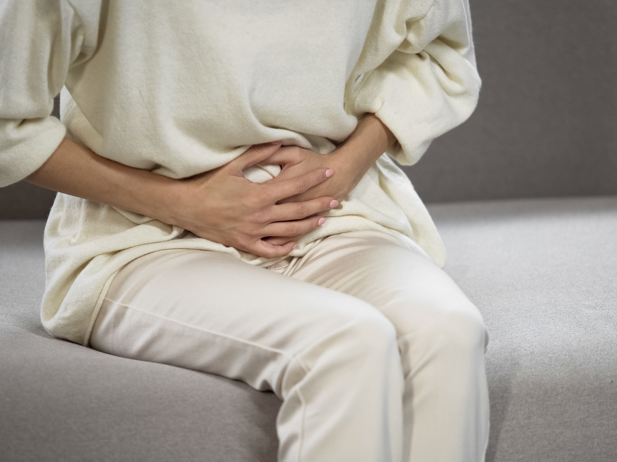 Mujer tocándose el abdomen con expresión de incomodidad por inflamación