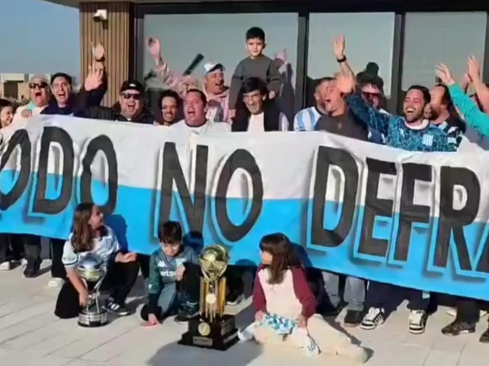 Gustavo Costas, técnico de Racing, visiblemente emocionado mientras recibe una bandera de parte de hinchas.