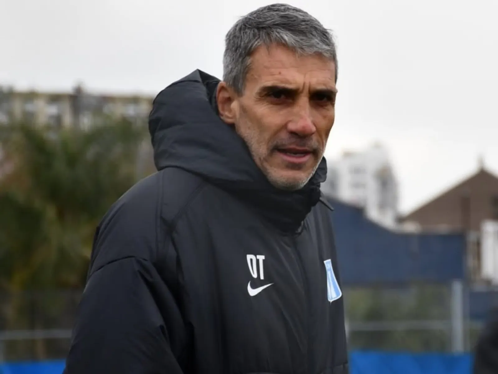 Juan Pablo Vojvoda, director técnico de Racing Club, observa un entrenamiento en el estadio Presidente Perón, visiblemente concentrado en la táctica de su equipo.