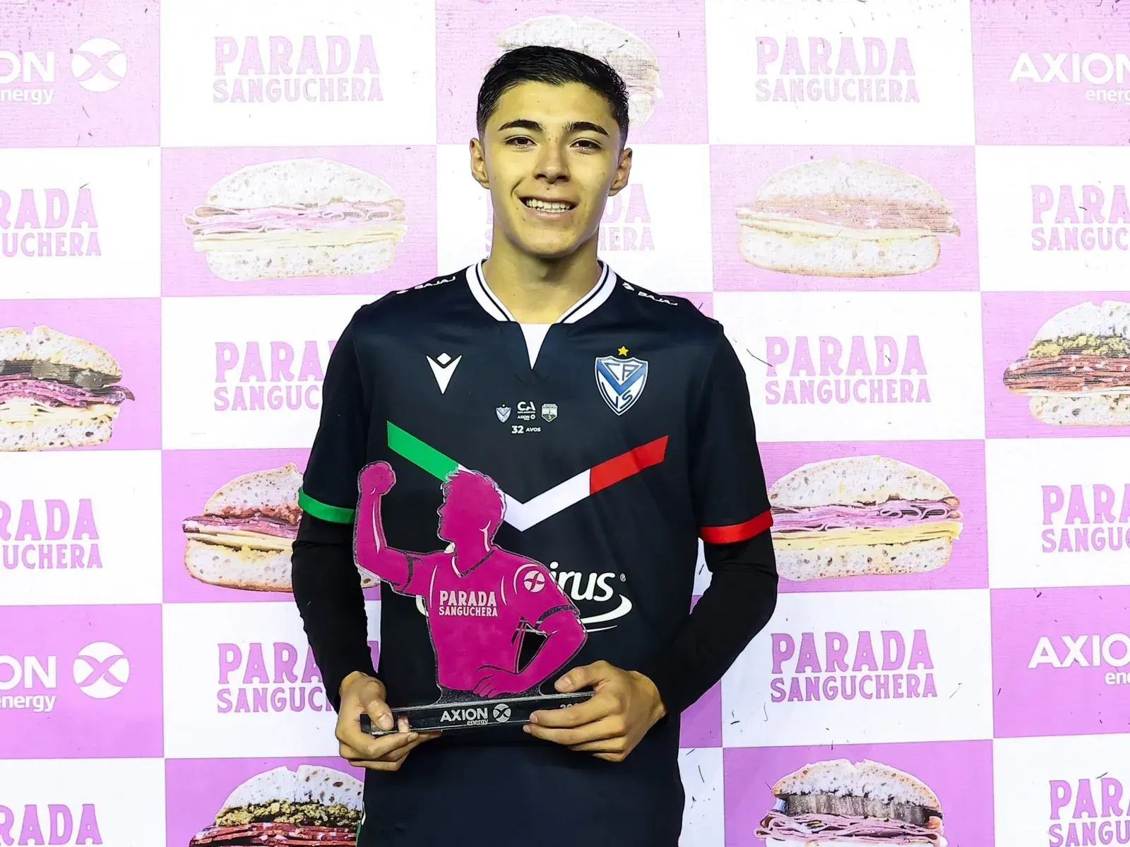 Un joven futbolista de Vélez Sarsfield con la pelota en los pies, preparándose para un partido.