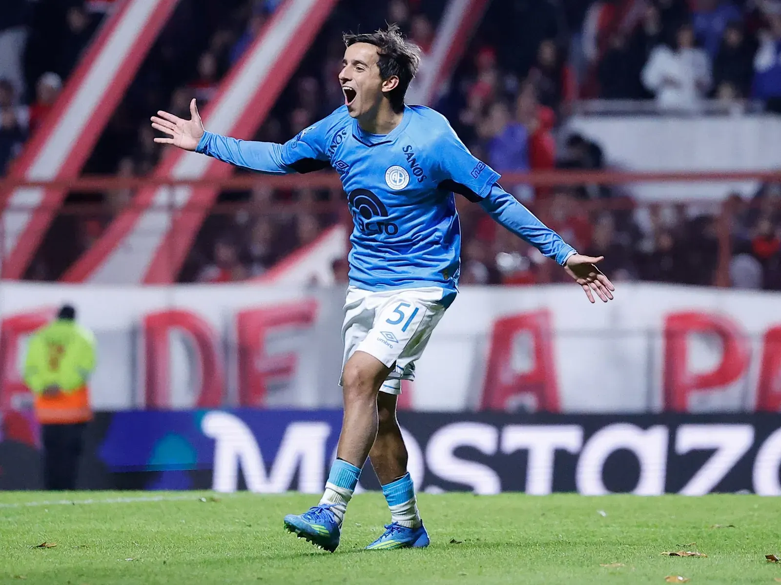 Ramiro Hernandes, jugador de Belgrano, sonríe y levanta los brazos tras anotar un gol importante.