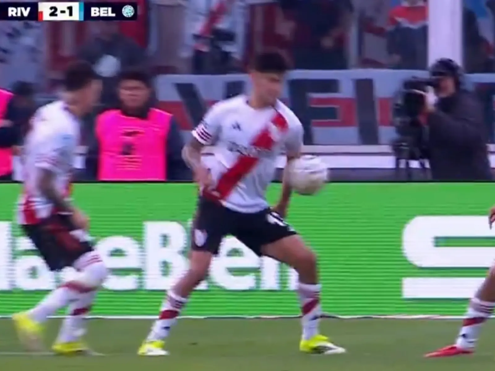Jugador de Rivero (Belgrano) interceptando un pase con el brazo dentro del área, mientras el árbitro observa.