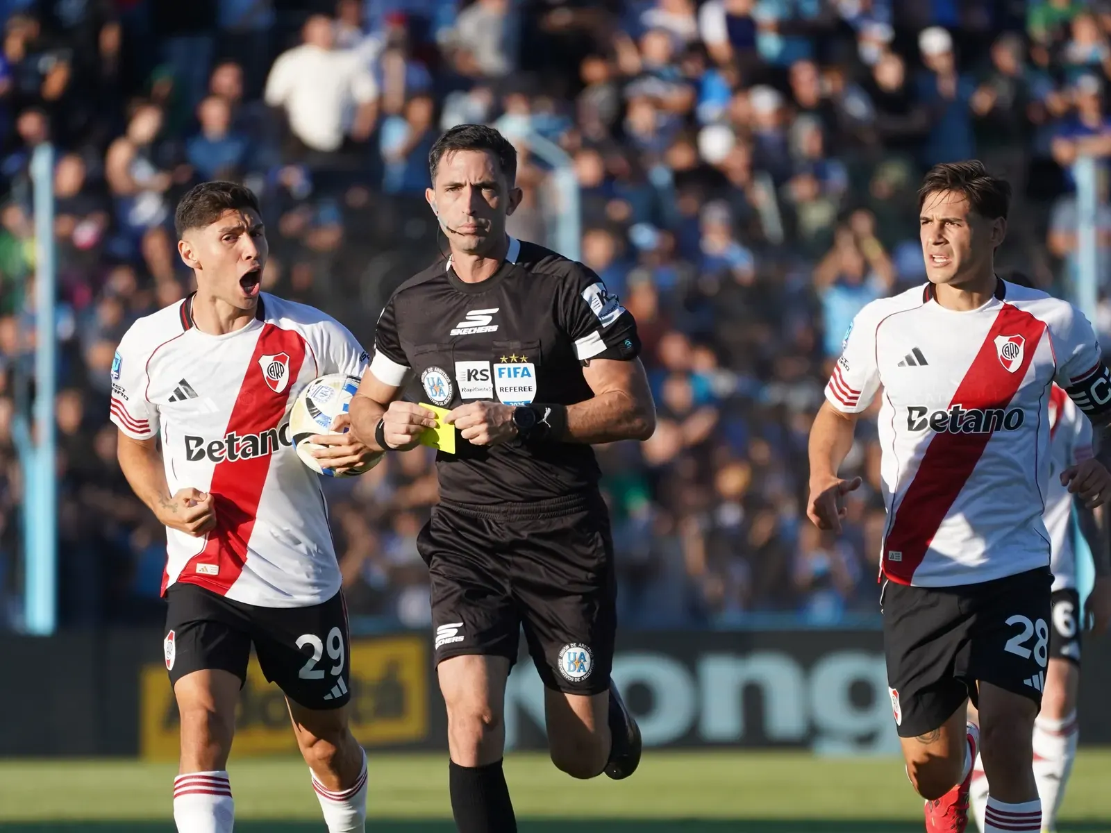Árbitro principal señalando el centro del campo en un partido de la Liga Profesional Argentina