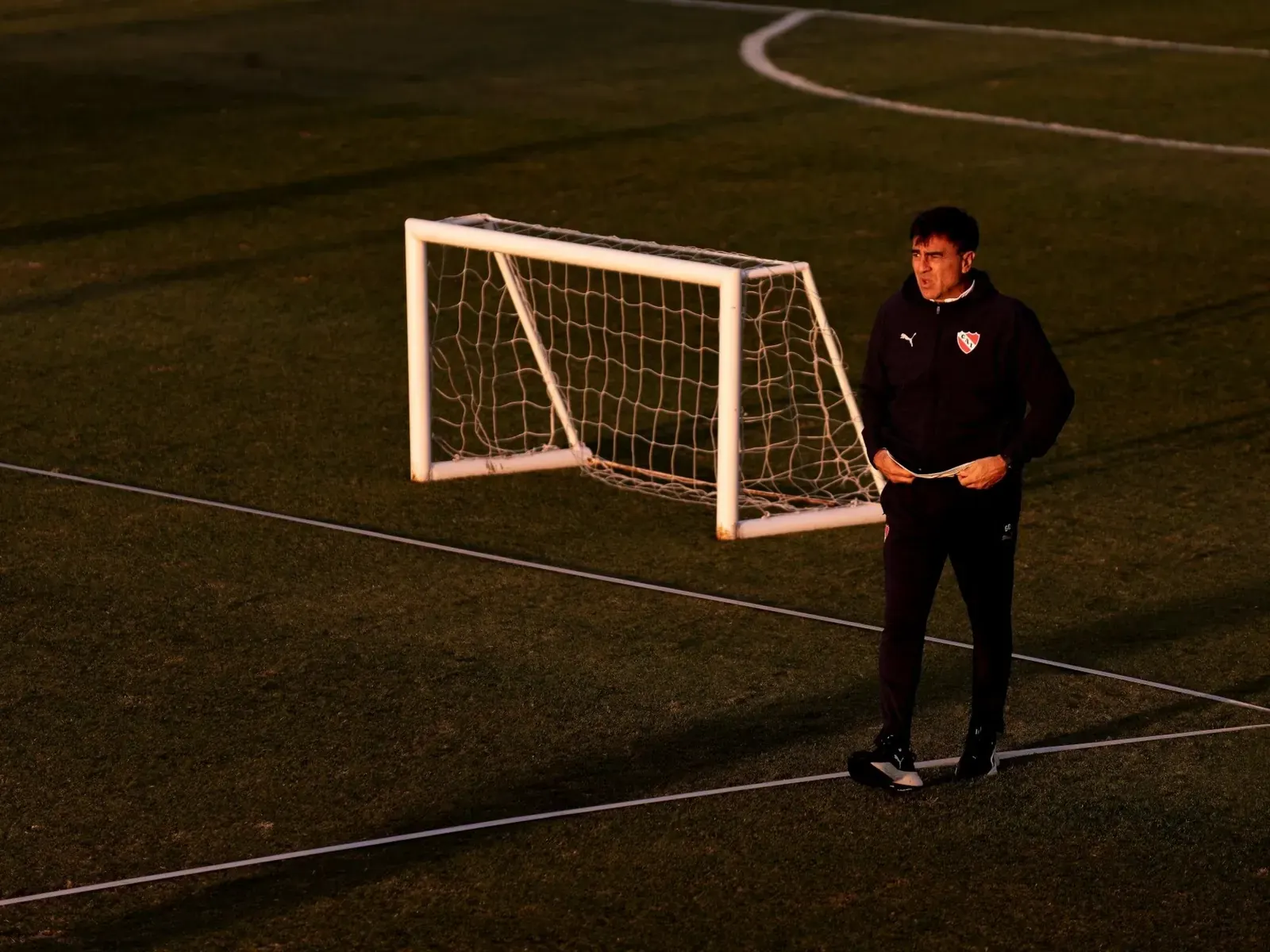 Gustavo Quinteros durante una práctica de Independiente, con jugadores al fondo en el predio de Villa Domínico.