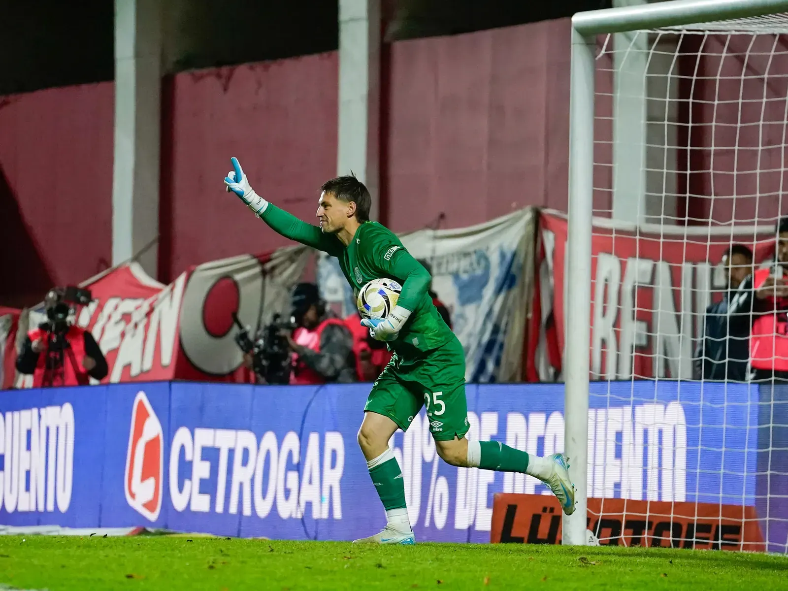 Arquero de Belgrano, Thiago Cardozo, atajando una pelota en un partido de fútbol.