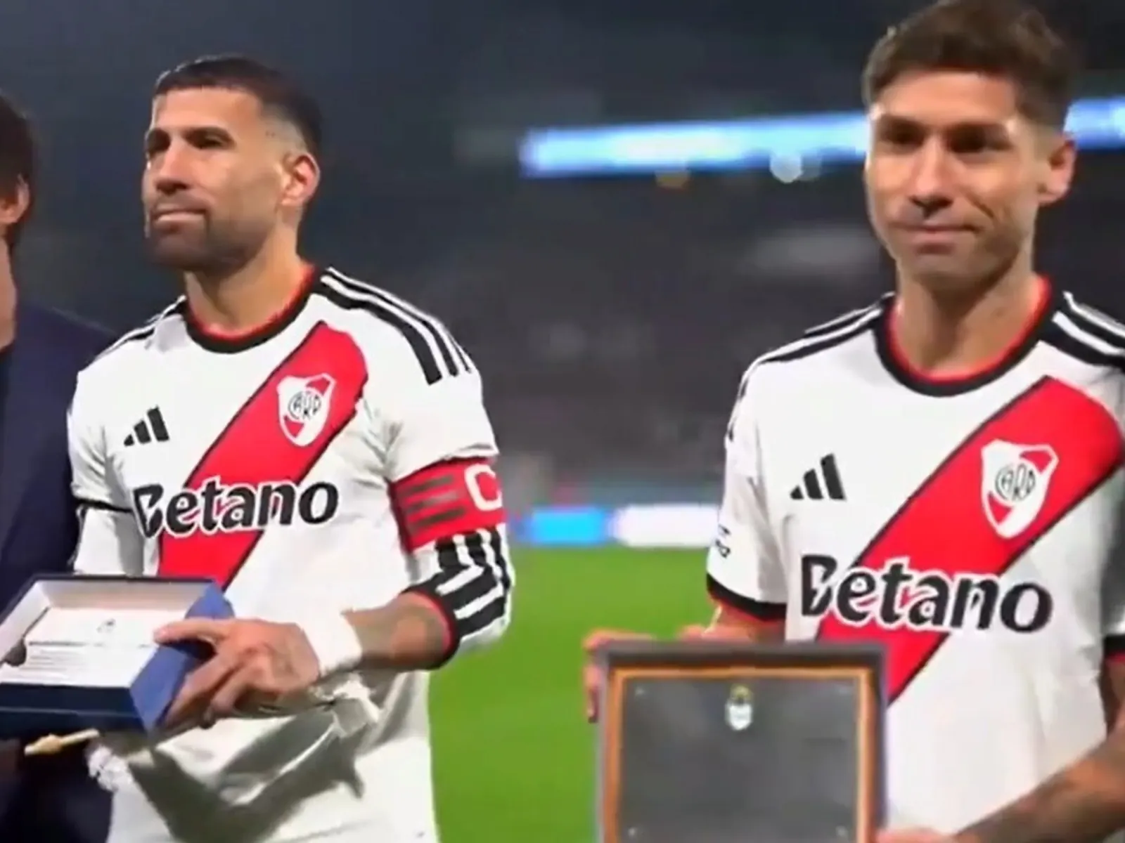 Nicolás Otamendi y Gonzalo Montiel posan con las plaquetas entregadas por la dirigencia de Gimnasia antes del partido ante River, en el Bosque de La Plata.